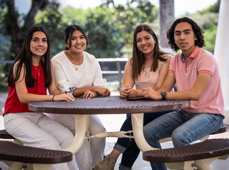 jóvenes seentados sonriendo a la cámara 