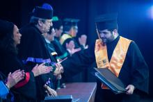 Basilio saluda y felicita a un chico de barba que se está graduando.